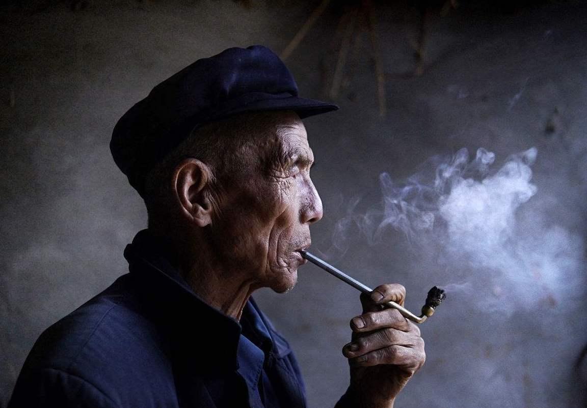 азиат курит трубку с табаком